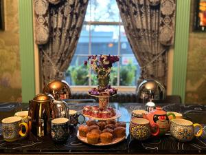 a table with cups and plates of pastries and tea pots at The Melville Hotel by Rokxy- Kings Cross in London