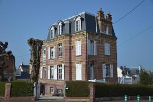 um grande edifício de tijolos com um telhado preto em Guesthouse La Mascotte em Villers-sur-Mer