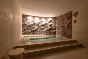 a bathroom with a tub with a stone wall at Olea Luxury Rooms & Spa in Split