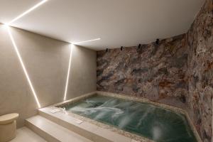 a jacuzzi tub in a bathroom with a stone wall at Olea Luxury Rooms & Spa in Split +118 photos