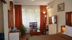ein Schlafzimmer mit Bett, Fernseher und Fenster in der Unterkunft Семеен Hotel Palitra in Warna