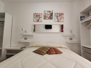 a white bedroom with a bed with two pillows on it at Villa Orsola in Villaputzu