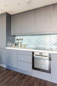 a kitchen with white cabinets and a sink at Luxury London Living in Perivale