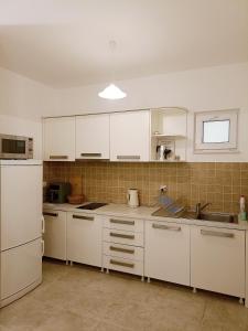 une cuisine avec des armoires blanches et un évier dans l'établissement Green Village studio, à Gornji Orahovac