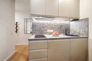 a kitchen with white cabinets and a bowl of fruit on the counter at Stylish gray studio near the city center in Vilnius