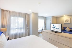 佛统Xen Hotel Nakhon Pathom - SHA PLUS的一间卧室配有一张床,并在橱柜上配有电视
