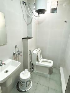 a white bathroom with a toilet and a sink at Hotel Emerald in Visakhapatnam