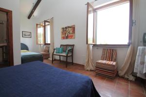 sypialnia z łóżkiem, oknem i krzesłami w obiekcie Villa Tresino B&B w mieście Santa Maria di Castellabate
