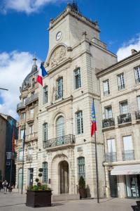 un bâtiment doté d'une tour d'horloge et de drapeaux. dans l'établissement Mercure Béziers, à Béziers