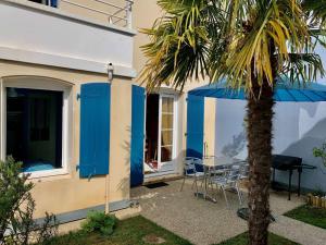 a house with a palm tree and a table and chairs at Mais 2 pièces mezza CHATELAILLON PLAGE - CL080-022 in Châtelaillon-Plage