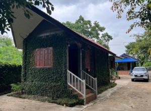 a building covered in ivy with a door and a porch at Rublom Resort Mae Taeng in Ban Pak Thang