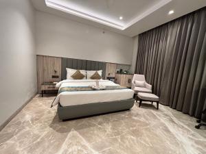 ein Schlafzimmer mit einem großen Bett und einem Stuhl in der Unterkunft The Eastern Grace Hotel in Buxar
