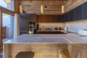 una cocina con una encimera grande con sillas. en Fleur des Alpes 501, en Mussillon 20 fotos más