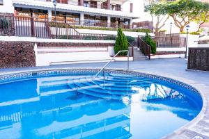 a swimming pool with blue water in front of a building at Coral Los Alisios in Los Cristianos