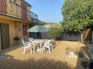 a patio with a table and chairs and an umbrella at Studio en rez-de-maison in Le Muy