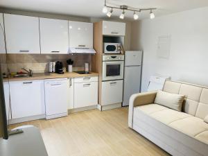 a kitchen with white cabinets and a couch in a room at Studio en rez-de-maison in Le Muy