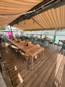 a restaurant with wooden tables and chairs on a deck at Strandhaus am Wörthersee in Velden am Wörthersee