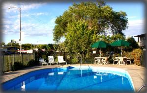 a swimming pool with chairs and umbrellas and a table at Black Canyon Motel in Montrose