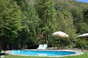 a swimming pool with two chairs and an umbrella at Cabañas Manquecura in Las Trancas