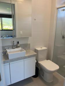 a white bathroom with a sink and a toilet at Apto em Home Clube na Praia de Palmas in Governador Celso Ramos