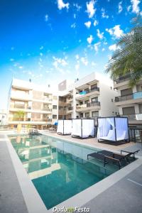 a swimming pool with two lounge chairs in front of a building at Apto em Home Clube na Praia de Palmas in Governador Celso Ramos