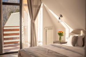 a bedroom with a bed and a balcony with a window at Yael Luxury Apartments 6 in Buşteni