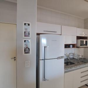 a refrigerator in a kitchen with white cabinets at Apartamento Villagio Olímpia in Olímpia