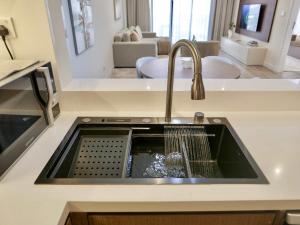 a kitchen counter with a sink with a dish washer at Ambient 1BR Apartment On The Beach at 5 Star Resort in Dubai