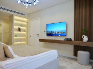 a bedroom with a bed and a tv on a wall at Ambient 1BR Apartment On The Beach at 5 Star Resort in Dubai