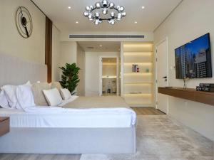 a bedroom with a large white bed and a chandelier at Ambient 1BR Apartment On The Beach at 5 Star Resort in Dubai