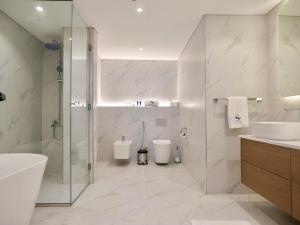 a bathroom with a shower and a toilet and a sink at Ambient 1BR Apartment On The Beach at 5 Star Resort in Dubai