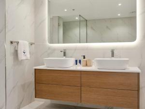 a bathroom with two sinks and a mirror at Ambient 1BR Apartment On The Beach at 5 Star Resort in Dubai