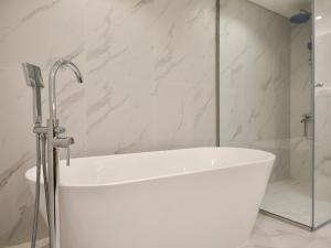 a white bath tub in a bathroom with a shower at Ambient 1BR Apartment On The Beach at 5 Star Resort in Dubai