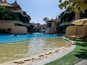 a swimming pool in a resort with a person in the water at Ambient 1BR Apartment On The Beach at 5 Star Resort in Dubai