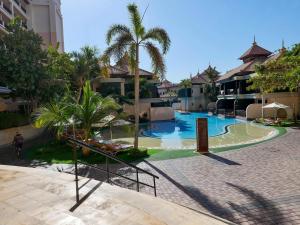 a swimming pool in a resort with palm trees at Ambient 1BR Apartment On The Beach at 5 Star Resort in Dubai