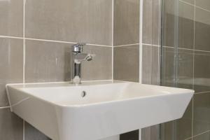 a white sink in a bathroom with tiled walls at Field View House in Brackley
