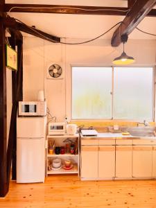 日南市にあるビーチまで徒歩一分の庭付き一棟貸し伊比井ステイのキッチン(白い冷蔵庫付)、窓