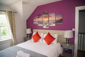 1 dormitorio con paredes moradas y 1 cama con almohadas rojas en The Dingle Pass Escape, en Dingle