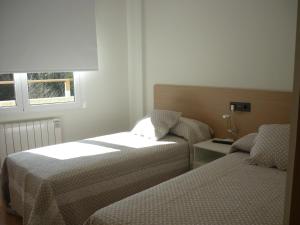 a hotel room with two beds and a window at Pensión-Albergue Puente Ribeira in Sarria