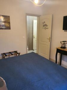 a bedroom with a blue bed and a white door at Les Feuillantines Perigord Noir in Saint-Cyprien