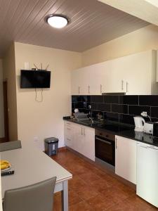 d'une cuisine avec des placards blancs et un mur en carrelage noir. dans l'établissement caminho da praia da maiata, à Porto da Cruz 10 autres photos