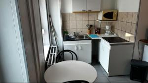 a small kitchen with a sink and a white stool at la chambre de Jade in Hirson