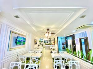 a restaurant with white tables and white chairs at Hotel La Perle in Hue