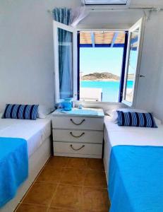 two beds in a room with a view of the ocean at Harmonia Beach House in Kimolos
