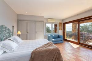 a bedroom with a large bed and a blue chair at Exquisite farmhouse in the Empordà Costa Brava in Vall-Llobrega +74 photos