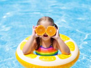 a little girl in a pool with two halves of an orange at Novotel Gdańsk Marina in Gdańsk
