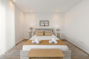 Un dormitorio blanco con una cama grande con dos almohadas. en Consolação Breeze Apartment, en Atouguia da Baleia