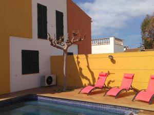 two pink chairs and a tree next to a pool at Villa Tonia in Cala en Blanes