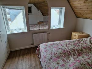 a bedroom with two windows and a bed with a bedspread at Lækker lejlighed 1 sal in Hinge