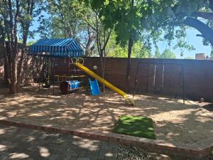 une aire de jeux avec un toboggan jaune dans un parc dans l'établissement Majestic Manor Guesthouse & Coffee Shop, à Bloemfontein